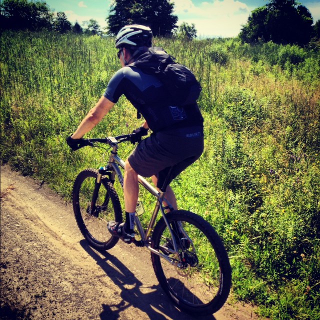 photo1 Mountian biking up a sunny dirt path in a meadow