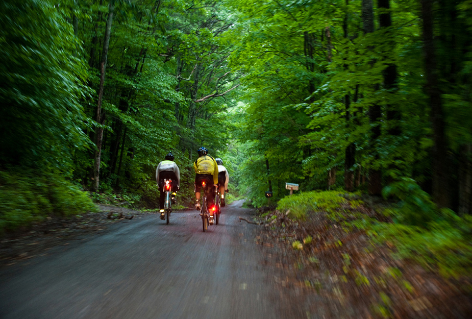 three riders fly downhill towards dusk