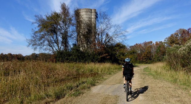 Cyclist on a dirt road near an old silo