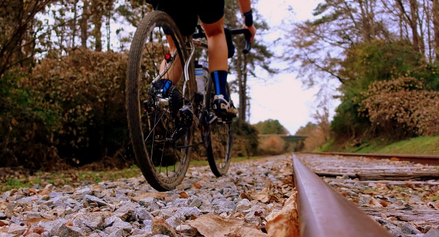A cyclist rides away along a train track