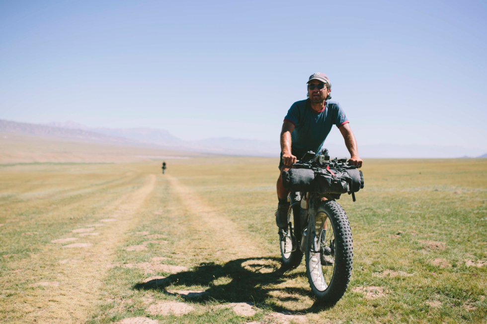 Jou Cruz leads another cyclist on a seemingly endless road in a wide open field on a cloudless day
