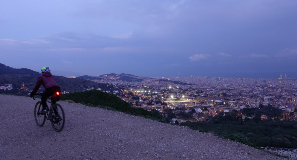 A cyclist admires a stunning city of Barcelona at dusk