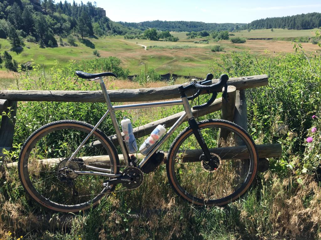 Mike J's Evergreen XX rests against a quaint wooden fence in front of a rolling field in Colorado
