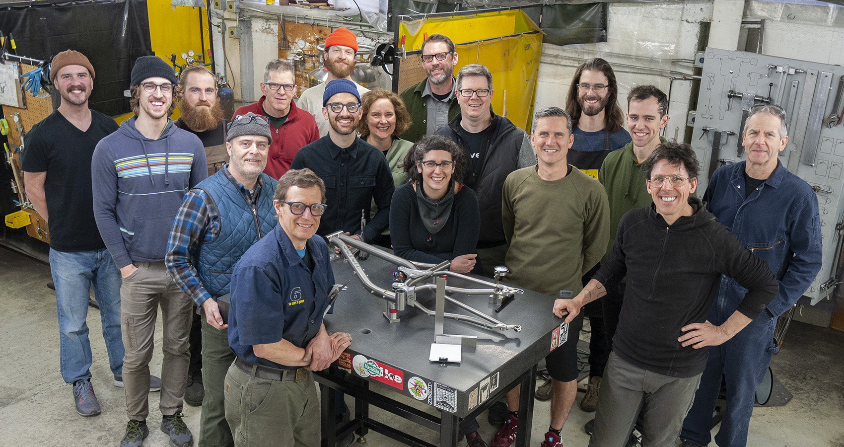 The crew at Seven Cycles poses around a surface plate with a curvy frame in process