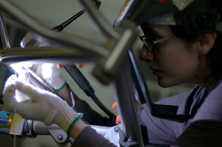 a TIG welder carefully works on a titanium frame