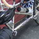 Matt and Suzi's titanium tandem with even more gear leans against a slatted red wall of a quaint country store