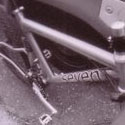 fisheye photo of a person's feet in front of a dual-suspension titanium mountain bike leaning against a truck